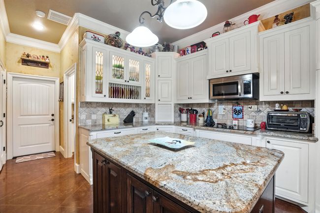 Kitchen featuring crown molding, backsplash, and white cabinetry | Image 11
