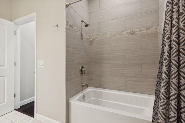 This is the oversized main level full bathroom. So fresh, so modern! Ample storage and cabinetry, granite countertops, tile flooring and ultra modern tile bath surround! Incredibly gorgeous!! | Image 22
