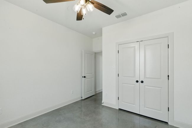 Unfurnished bedroom with concrete floors, baseboards, a closet, and ceiling fan | Image 23