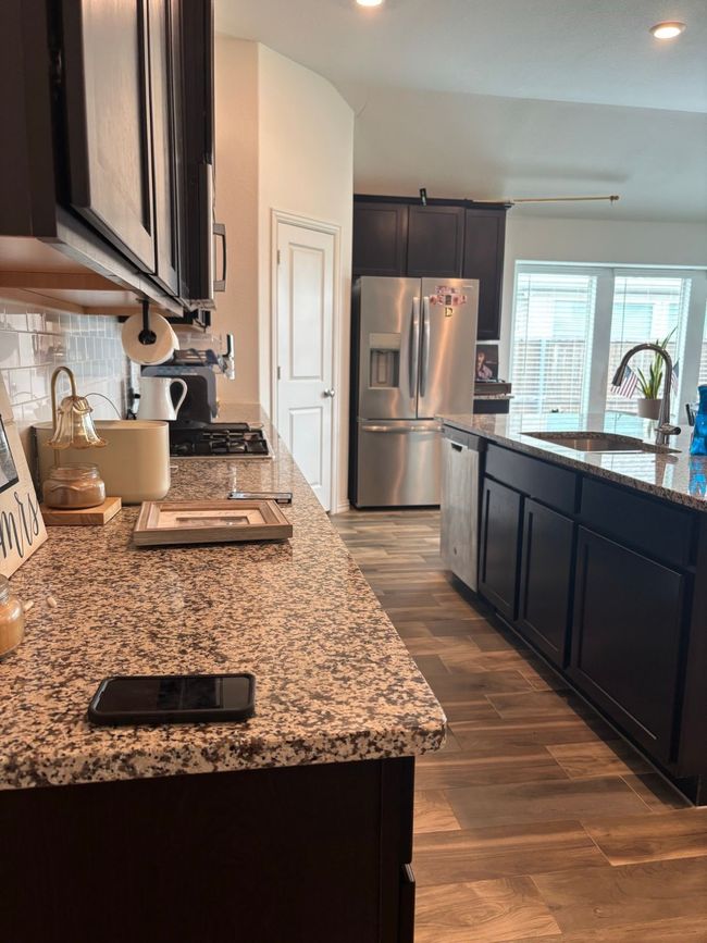 Kitchen with appliances with stainless steel finishes, light stone countertops, wood finished floors, recessed lighting, and decorative backsplash | Image 9