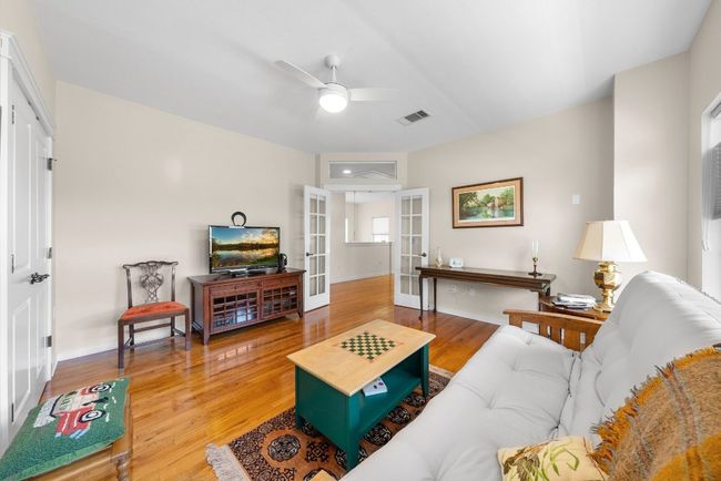 Living area with wood finished floors, visible vents, french doors, baseboards, and ceiling fan | Image 24
