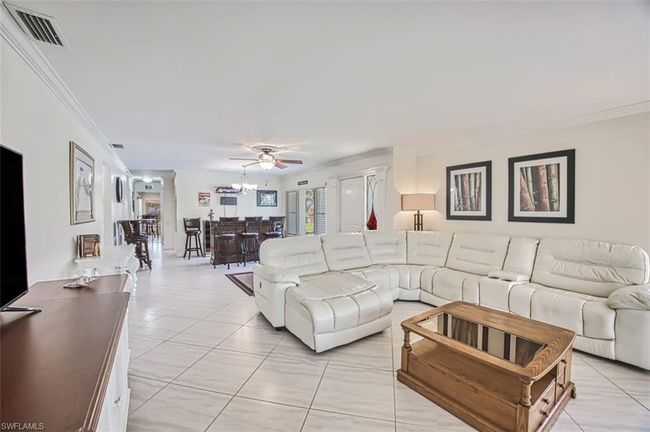 Living room with ornate columns, visible vents, crown molding, and a ceiling fan | Image 12