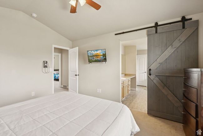Primary Bedroom featuring lofted ceiling, a barn door, light carpet, and ceiling fan | Image 25