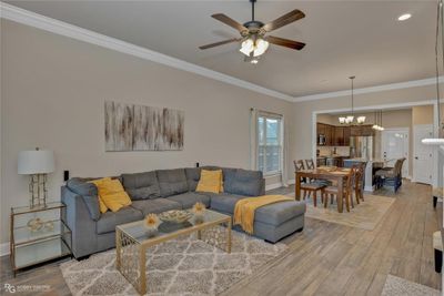 Living room featuring crown molding, ceiling fan with notable chandelier, and light wood-type flooring | Image 2