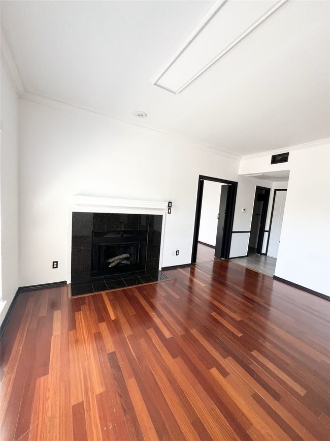 living room with a tile fireplace, visible vents, crown molding, and wood finished floors | Image 4