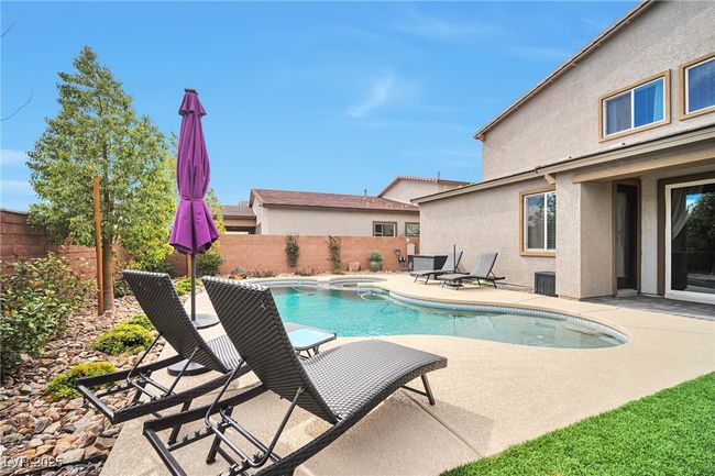 View of swimming pool featuring a fenced backyard, central air condition unit, a pool with connected hot tub, and a patio | Image 29