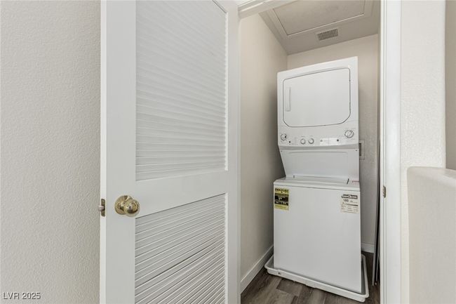 Laundry area featuring stacked washer / drying machine, laundry area, baseboards, visible vents, and dark wood-type flooring | Image 20