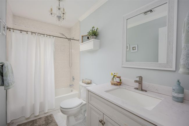 Full bathroom featuring shower / tub combo, vanity, tile patterned floors, ornamental molding, and a chandelier | Image 13