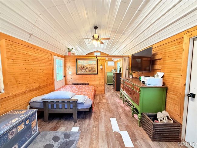 Bedroom with wooden walls, wood finished floors, and lofted ceiling | Image 13