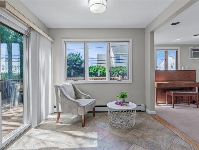 Sitting room with a wall mounted AC, stone finish flooring, baseboards, a baseboard heating unit, and carpet | Image 11