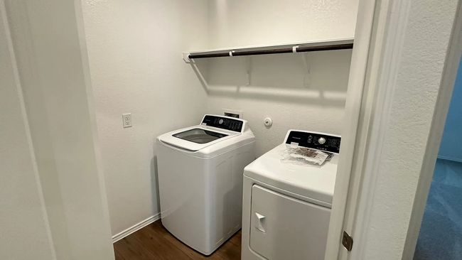 Washroom with a textured wall, dark wood-type flooring, and washing machine and dryer | Image 31