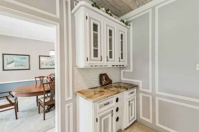 Close up of the pretty built-in dry bar with granite countertop and glass tile backsplash | Image 10
