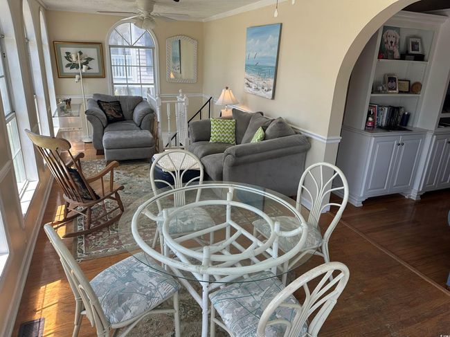 Living area featuring dark wood-type flooring, arched walkways, a ceiling fan, ornamental molding, and built in shelves | Image 15