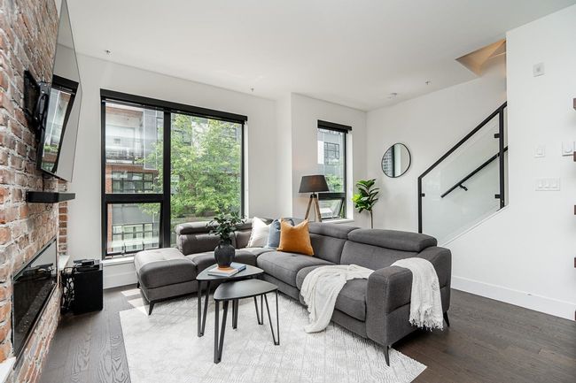 Living area with wood finished floors, a brick fireplace, and stairway | Image 10