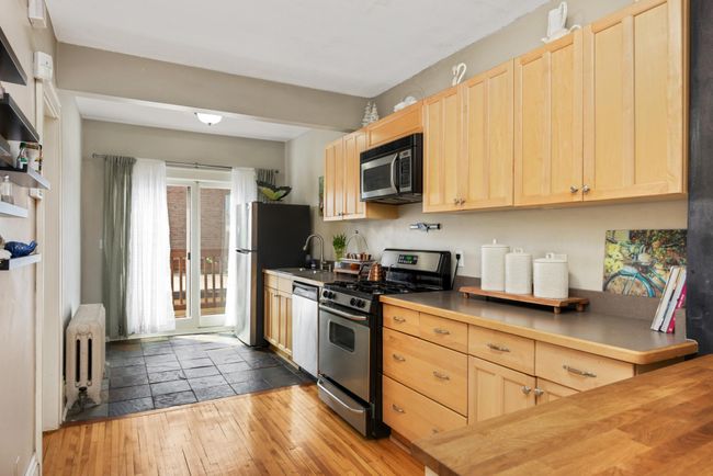 This gorgeous updated kitchen includes stainless steel appliances and is complimented by modern slate tile. This doorway offers a second exit from the condo to the deck, which includes a staircase leading to the garage. | Image 13