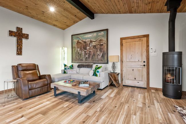Living area featuring baseboards, lofted ceiling with beams, wooden ceiling, light wood-style flooring, and a wood stove | Image 17