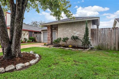 Greenery offering manicured flower beds, front gate access to the back yard and a shaded tree. | Image 2