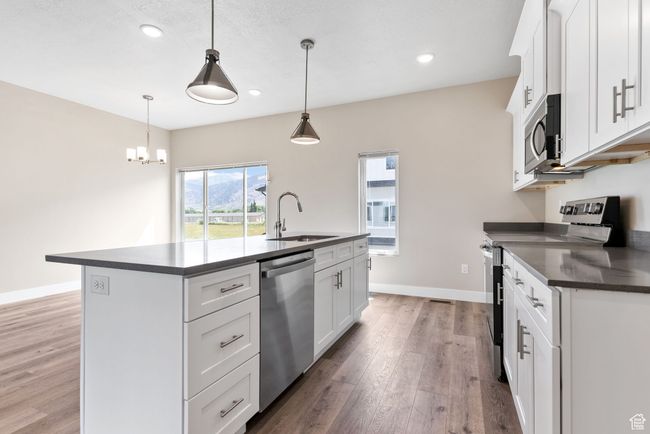 Kitchen with dark countertops, a sink, stainless steel appliances, and light wood-type flooring | Image 4