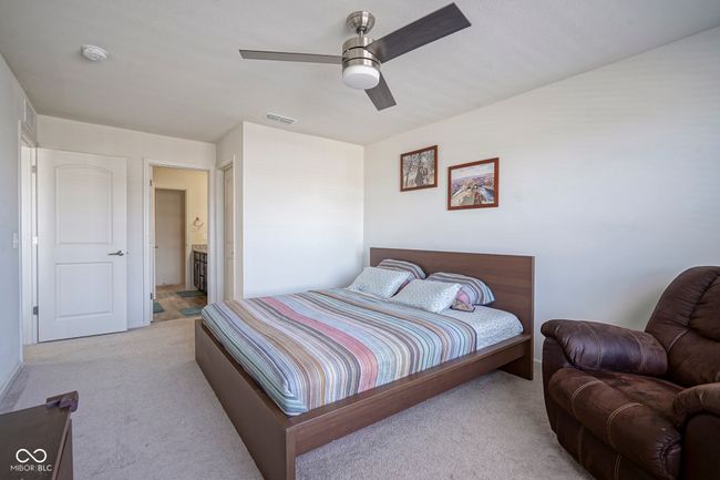 bedroom with light colored carpet, visible vents, ensuite bathroom, and a ceiling fan | Image 30
