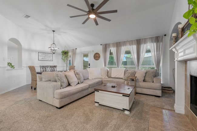 Living area featuring ceiling fan, a fireplace, a chandelier, arched walkways, and lofted ceiling | Image 16