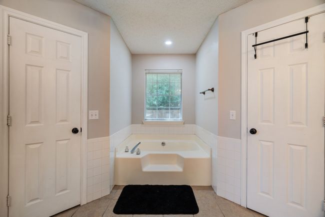 Bathroom with tile walls, a wainscoted wall, tile patterned floors, a bath, and recessed lighting | Image 10