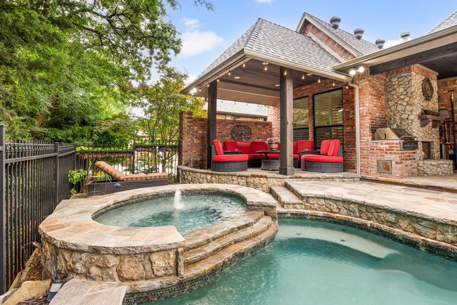 View of heated spa and one of two outdoor living spaces. The pool includes a sun deck and submerged seating | Image 37
