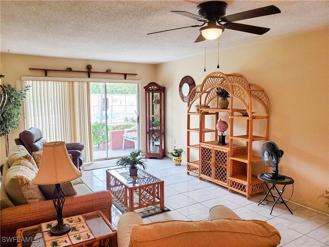 Living area with a ceiling fan, tile patterned floors, and a textured ceiling | Image 5