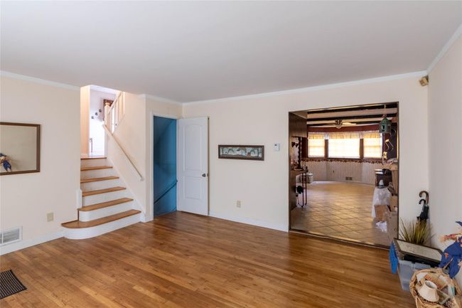 Unfurnished living room with stairs, visible vents, wood finished floors, and ornamental molding | Image 7