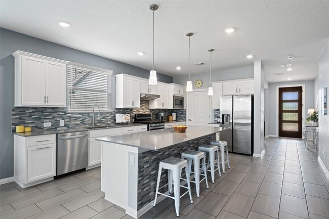The gourmet kitchen features a large center island with bar seating. | Image 11