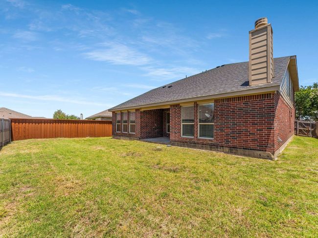 Rear view of house with a fenced backyard, brick siding, roof with shingles, and a chimney | Image 38