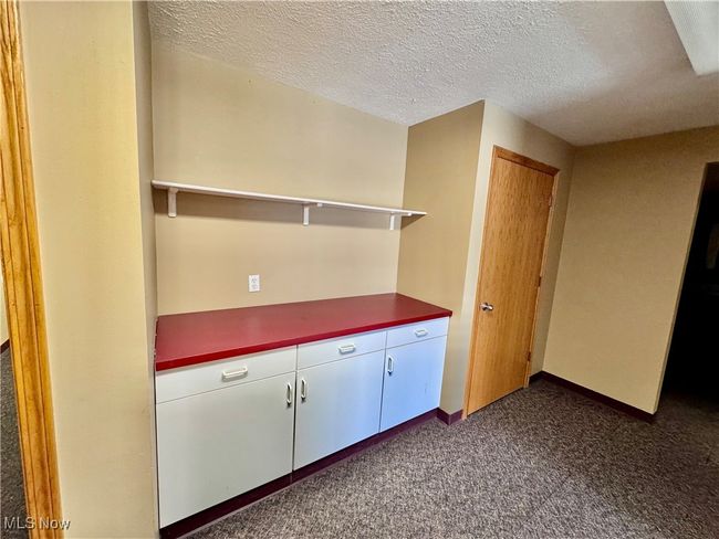 Kitchen with dark carpet and a textured ceiling | Image 9