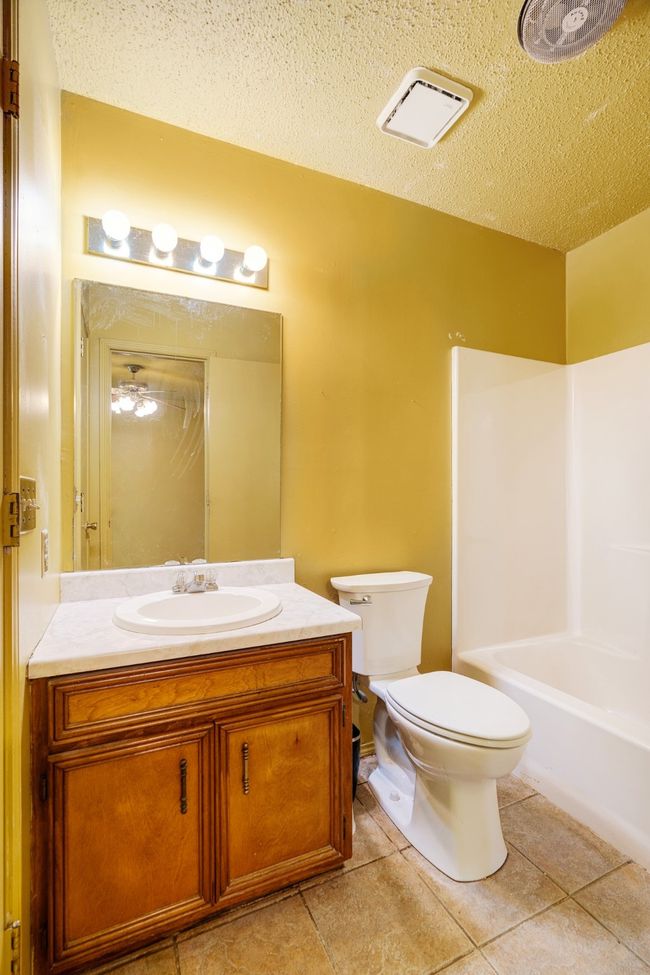 Bathroom featuring vanity, a textured ceiling, tile patterned floors, and shower / bath combination | Image 8