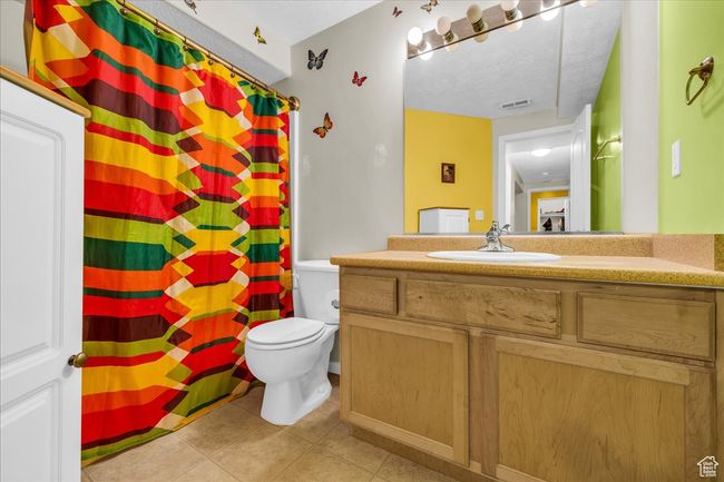 Bathroom with a shower with curtain, visible vents, toilet, vanity, and tile patterned flooring | Image 13