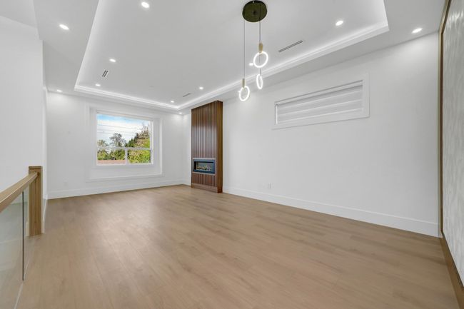 Unfurnished living room featuring a raised ceiling, a fireplace, light wood finished floors, baseboards, and recessed lighting | Image 9