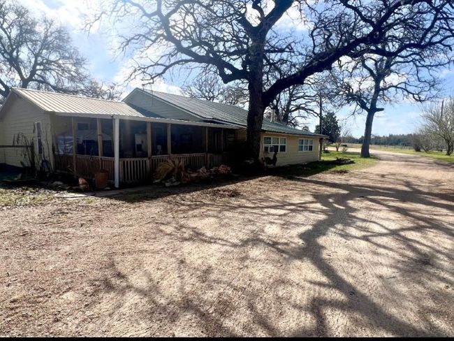 Rear view of property featuring metal roof, covered porch, and driveway | Image 16