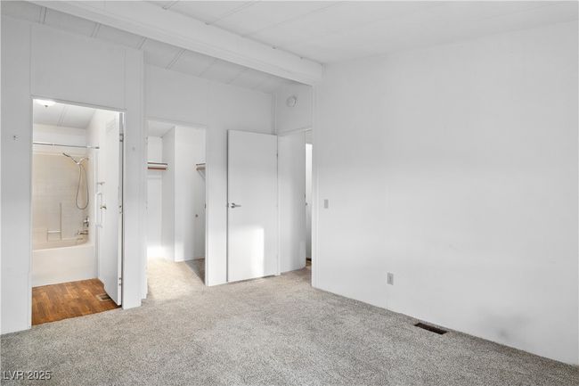 Primary bedroom featuring carpet floors, vaulted ceiling with beams, visible vents, a spacious closet, and ensuite bath | Image 22