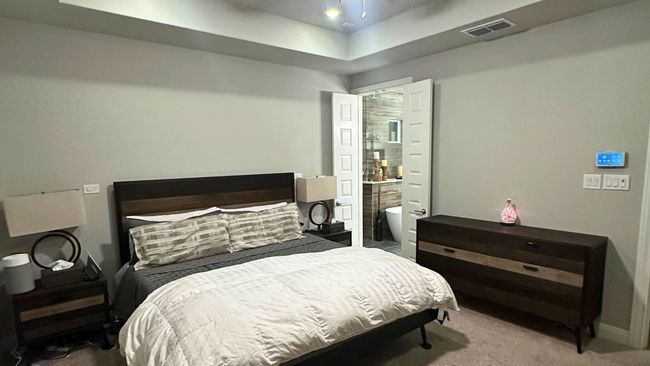 Carpeted bedroom with a tray ceiling and connected bathroom | Image 7
