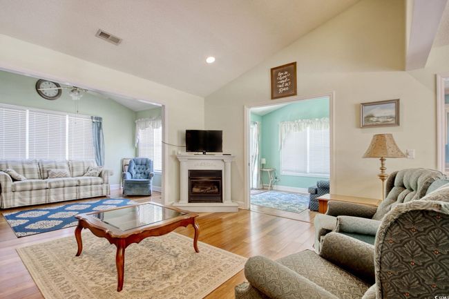 Living room featuring wood finished floors, high vaulted ceiling, a glass covered fireplace, and recessed lighting | Image 19