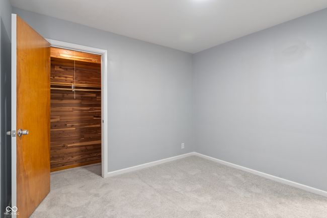 unfurnished bedroom with carpet floors, baseboards, wooden walls, and a closet | Image 28