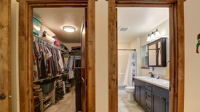 Full bath with a textured ceiling, toilet, double vanity, a walk in closet, and tile patterned flooring | Image 20