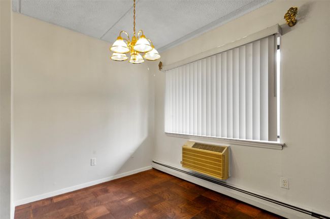 Empty room featuring a baseboard heating unit, a textured ceiling, a chandelier, and a wall mounted air conditioner | Image 13