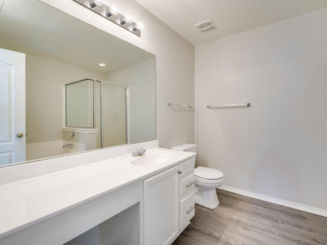 Primary bathroom featuring spacious vanity, luxury vinyl wood-look flooring, separate shower and garden-style tub. | Image 18
