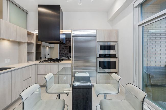 Kitchen featuring light countertops, modern cabinets, light brown cabinets, ventilation hood, and built in appliances | Image 8