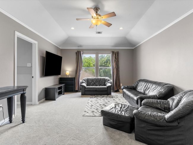 Living area with light carpet, ceiling fan, vaulted ceiling, crown molding, and recessed lighting | Image 25