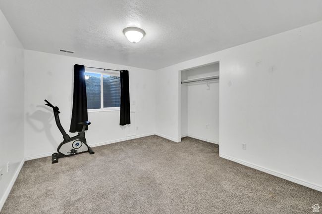 Unfurnished bedroom featuring carpet flooring, baseboards, a textured ceiling, visible vents, and a closet | Image 33