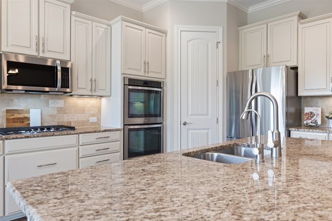 Kitchen with crown molding, light stone countertops, a sink, backsplash, and stainless steel appliances | Image 14