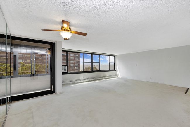 Empty room featuring ceiling fan, a textured ceiling, and baseboard heating | Image 4