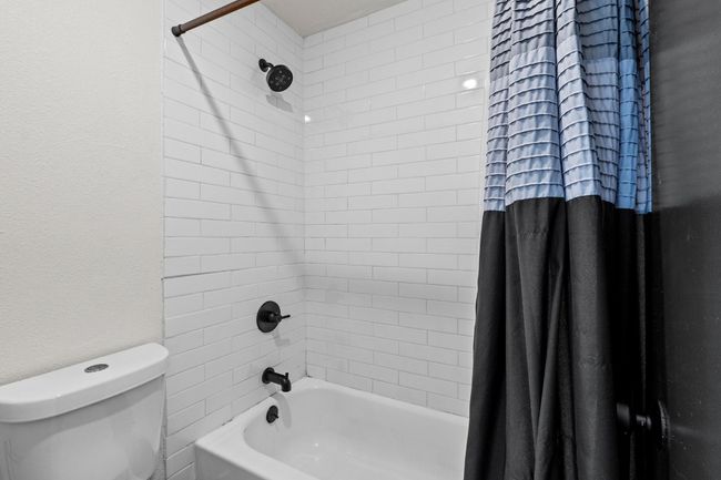 Bathroom with shower / bath combo with shower curtain, toilet, and a textured wall | Image 22