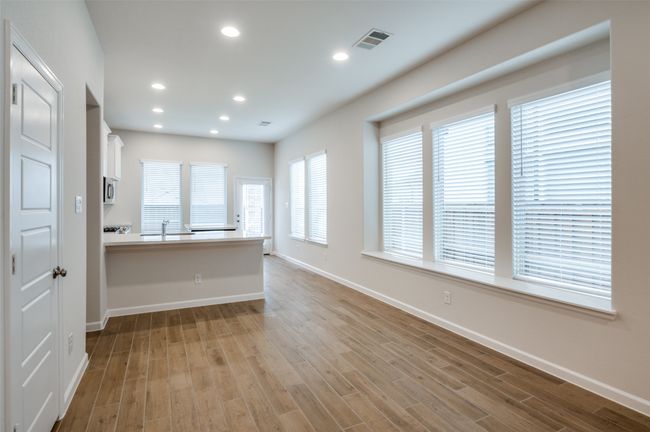 Kitchen featuring sink, kitchen peninsula, light hardwood / wood-style floors, white cabinetry, and a breakfast bar area | Image 5