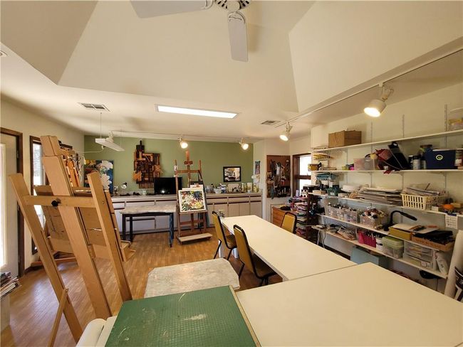 Office area featuring a ceiling fan, wood finished floors, a healthy amount of sunlight, and visible vents | Image 54